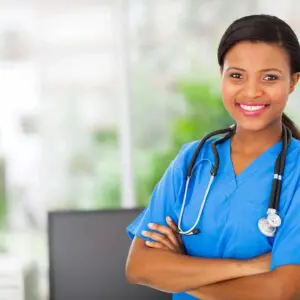 A woman in blue scrubs and stethoscope with her arms crossed.