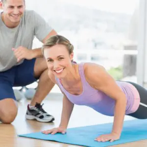 A man and woman doing push ups on the floor.