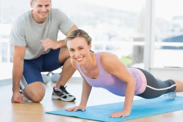 A man and woman doing push ups on the floor.